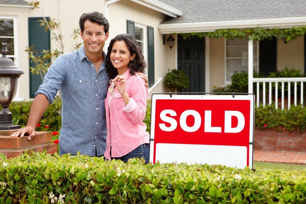 Couple outside home with sold sign