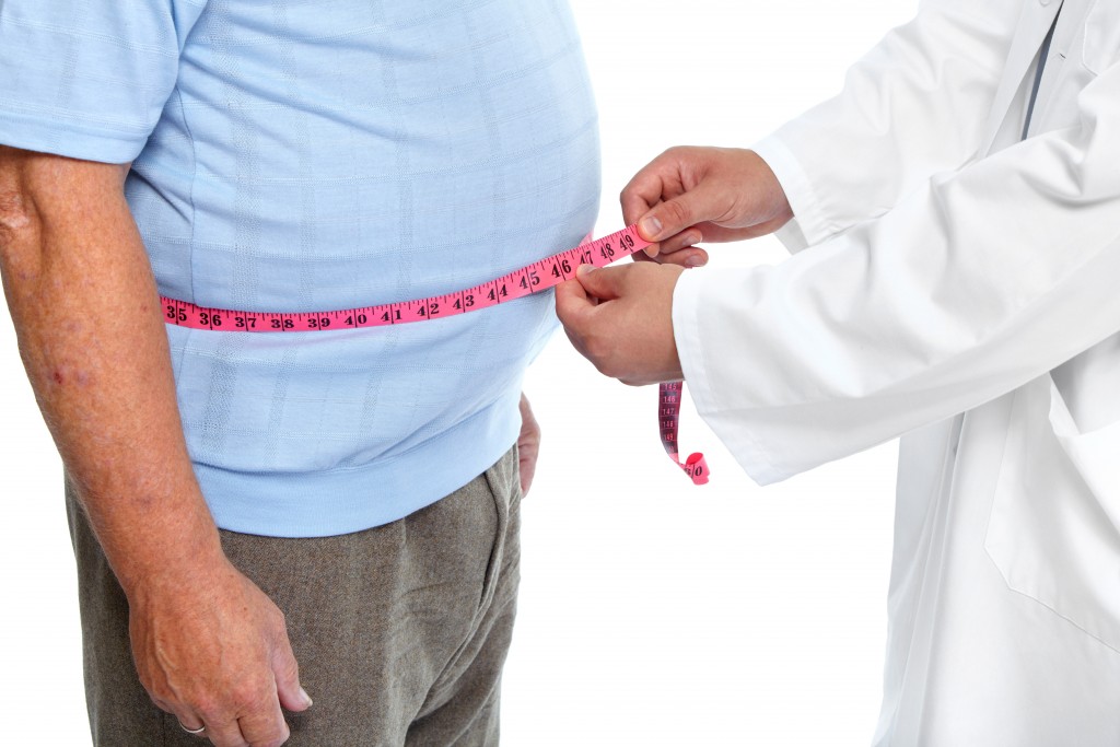 Doctor measuring obese man waist body fat. Obesity and weight loss.