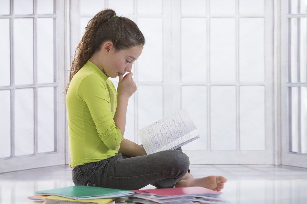 little girl thumb sucking while reading book