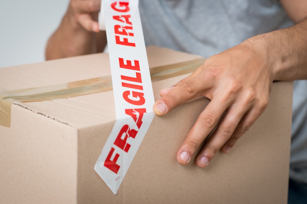Man packing a box with fragile tape