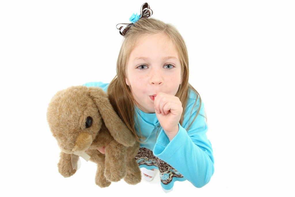 girl carrying a teddy bear and sucking her thumb