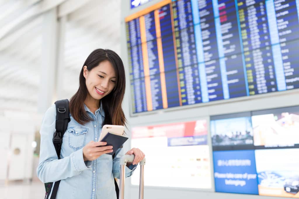 a woman holding a passport and luggage in an airport