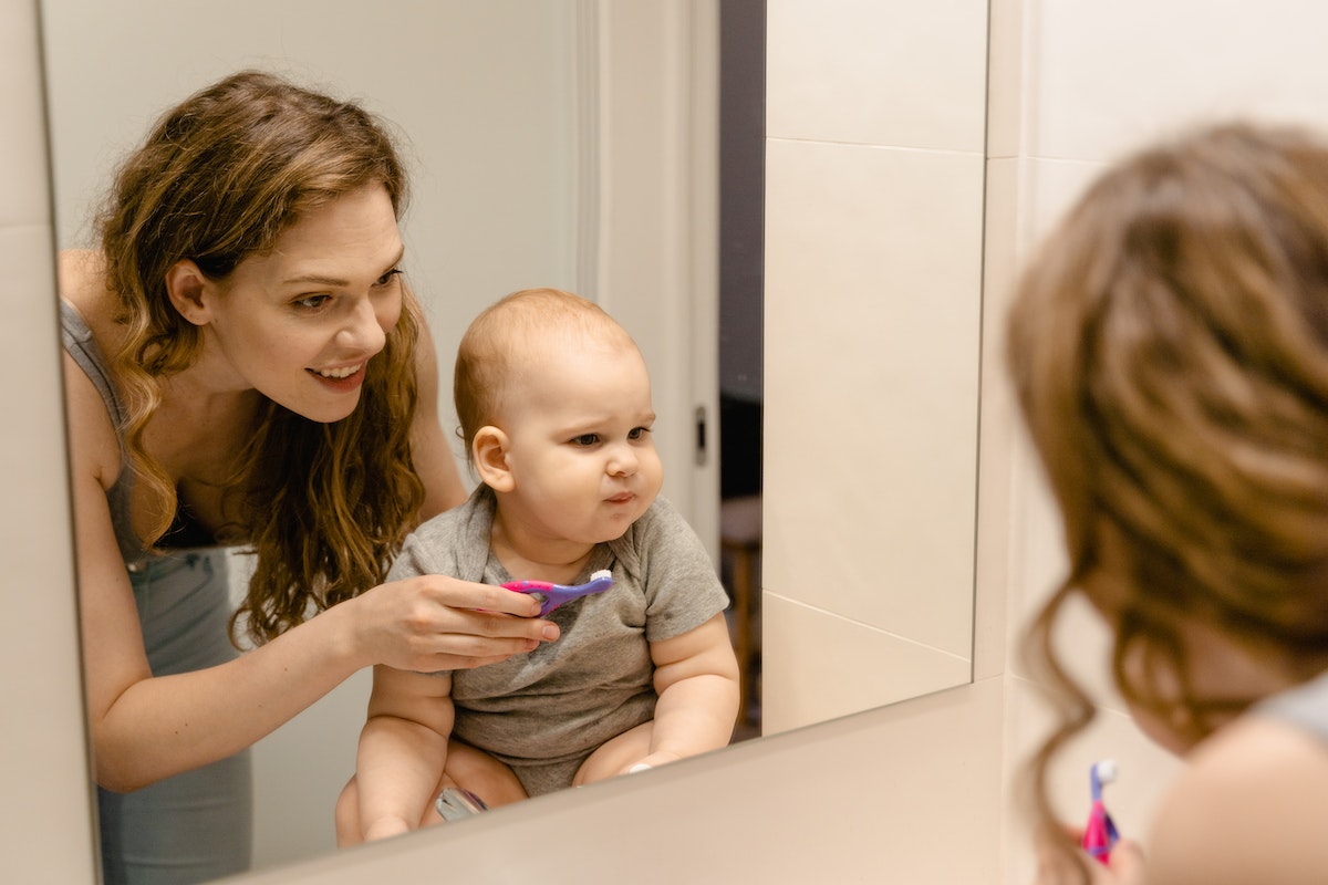 mom trying to brush teeth of infant